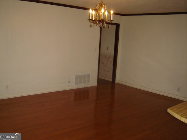 spare room with a chandelier, dark hardwood / wood-style flooring, and ornamental molding