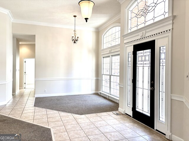 entrance foyer featuring crown molding, light colored carpet, a textured ceiling, and an inviting chandelier