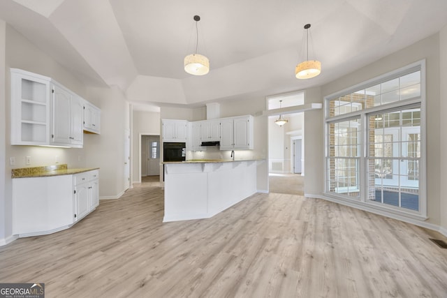 kitchen featuring kitchen peninsula, white cabinetry, oven, and light hardwood / wood-style floors