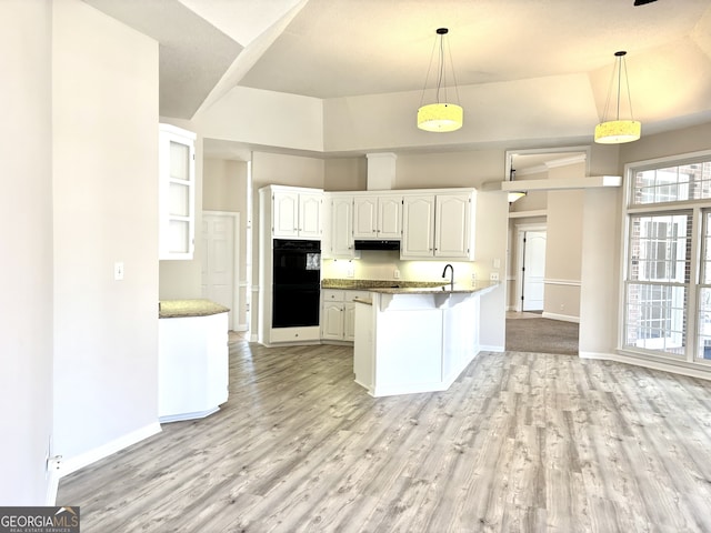 kitchen featuring kitchen peninsula, double oven, light hardwood / wood-style flooring, white cabinetry, and hanging light fixtures