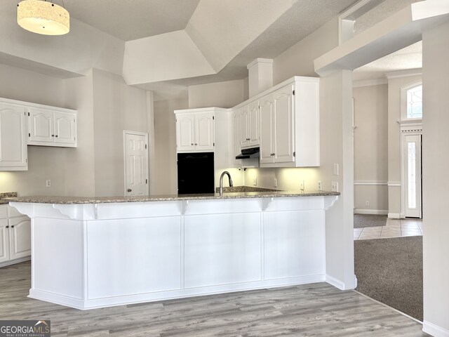 kitchen featuring light hardwood / wood-style floors, light stone counters, white cabinetry, and kitchen peninsula