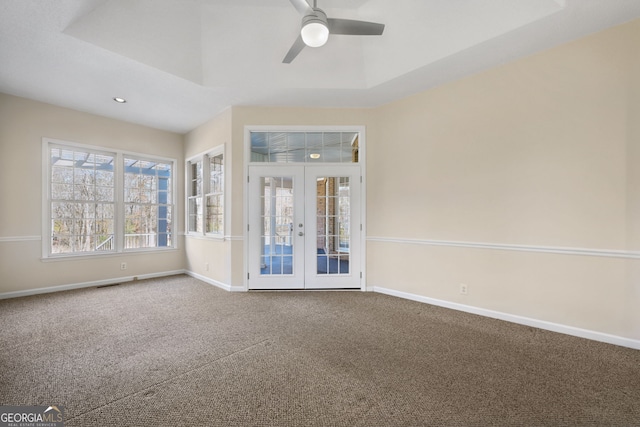 carpeted empty room featuring a raised ceiling, ceiling fan, and french doors