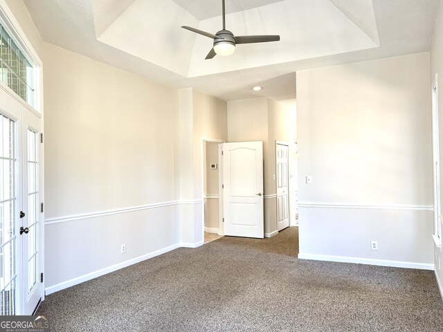 spare room featuring a tray ceiling, ceiling fan, carpet flooring, and french doors