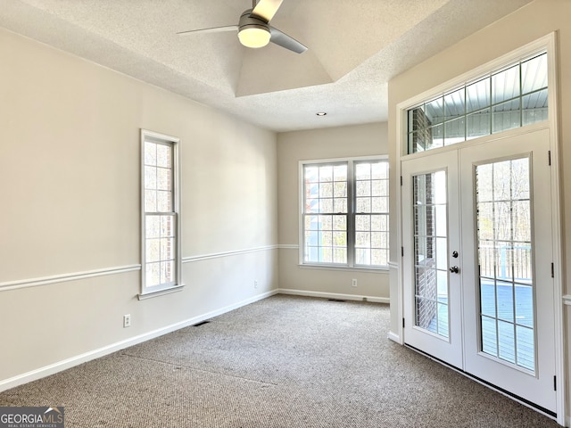 carpeted spare room featuring french doors, a healthy amount of sunlight, and a textured ceiling