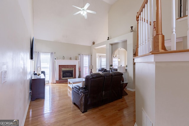 living room with a wealth of natural light, ceiling fan, light wood-type flooring, and high vaulted ceiling