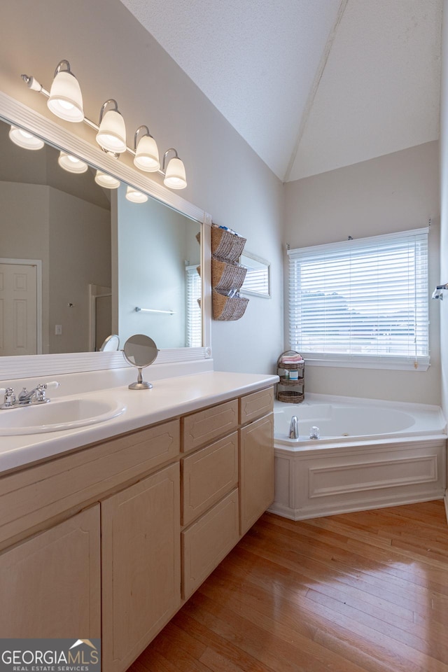 bathroom featuring wood-type flooring, vanity, and lofted ceiling