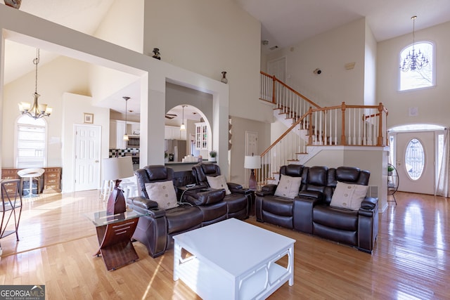 living room with high vaulted ceiling, light hardwood / wood-style floors, and a notable chandelier