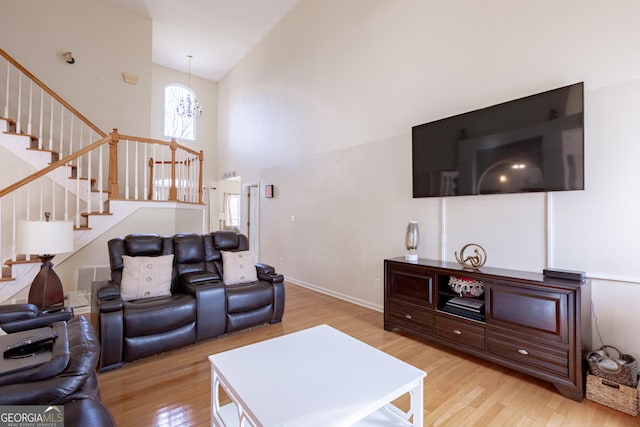 living room featuring a chandelier, high vaulted ceiling, and light hardwood / wood-style flooring