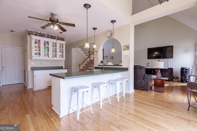 kitchen with white cabinets, hanging light fixtures, ceiling fan, light hardwood / wood-style floors, and kitchen peninsula