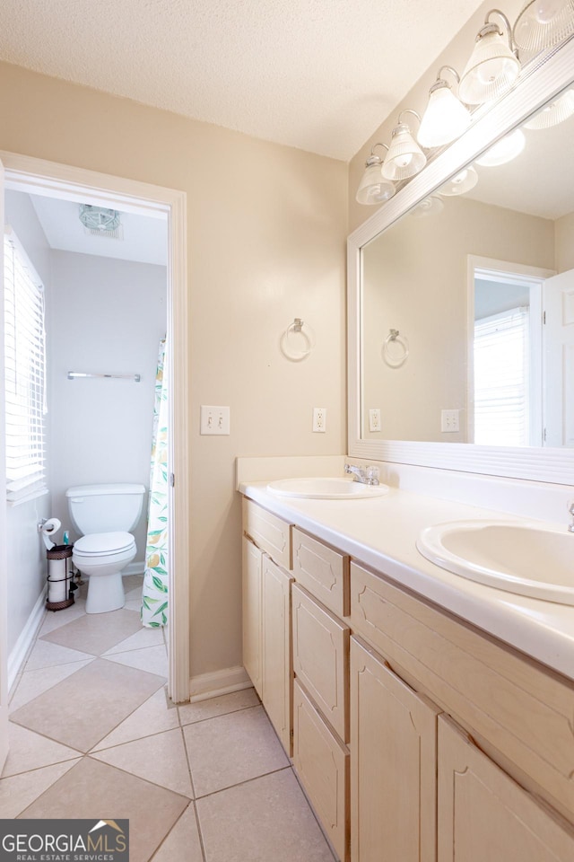 bathroom featuring tile patterned flooring, vanity, toilet, and a textured ceiling