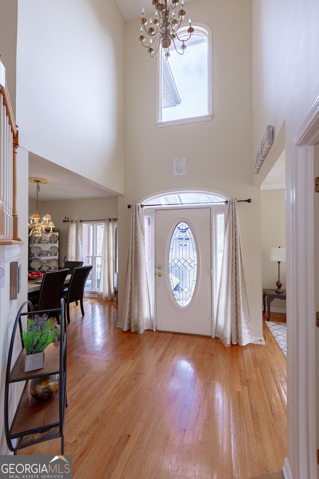 foyer with a notable chandelier, light hardwood / wood-style floors, and a high ceiling