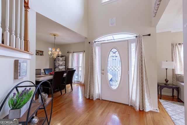 foyer featuring light hardwood / wood-style floors, crown molding, and a notable chandelier