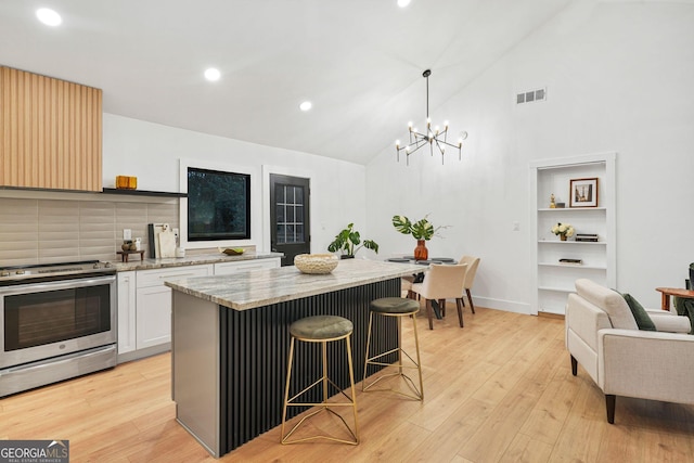 kitchen featuring pendant lighting, a breakfast bar, stainless steel stove, light hardwood / wood-style floors, and white cabinetry