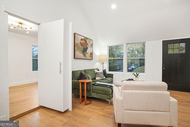 living room featuring hardwood / wood-style floors, lofted ceiling, and a chandelier