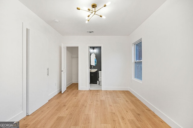 unfurnished bedroom with ensuite bath, sink, a notable chandelier, light hardwood / wood-style floors, and a closet