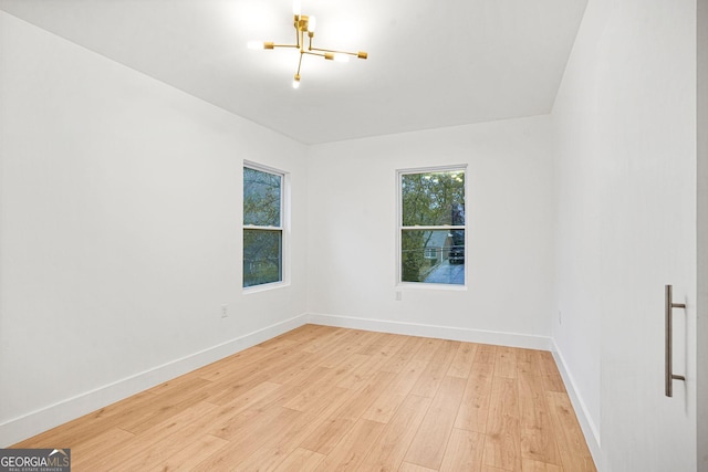 empty room with an inviting chandelier and light wood-type flooring