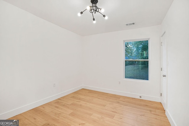 empty room featuring light hardwood / wood-style floors and a notable chandelier