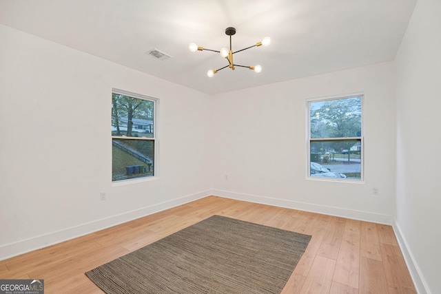 spare room with a notable chandelier and hardwood / wood-style flooring