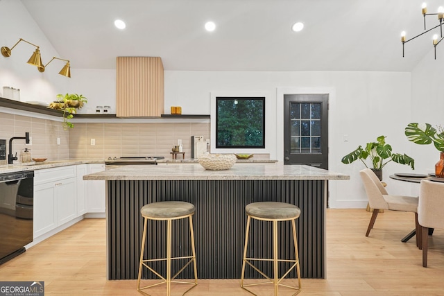 kitchen with white cabinetry, a breakfast bar, a kitchen island, and light hardwood / wood-style floors