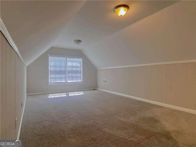 additional living space with carpet, wooden walls, and lofted ceiling