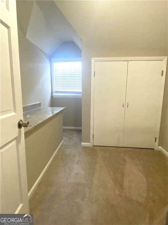 additional living space featuring lofted ceiling and light carpet