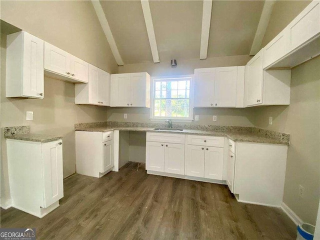 kitchen with light stone countertops, dark hardwood / wood-style flooring, sink, white cabinets, and vaulted ceiling with beams