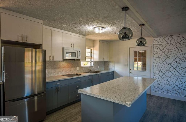 kitchen featuring stainless steel fridge, decorative light fixtures, dark wood-type flooring, and sink