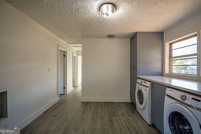 clothes washing area with washer and clothes dryer, dark wood-type flooring, and a textured ceiling