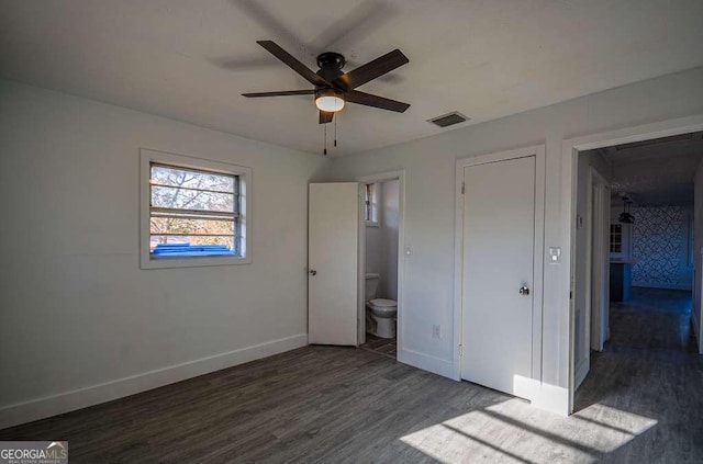 unfurnished bedroom with ceiling fan, dark wood-type flooring, and connected bathroom