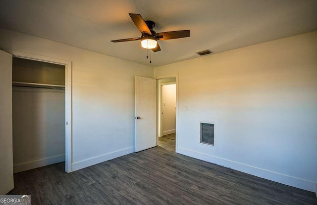 unfurnished bedroom featuring ceiling fan, dark hardwood / wood-style flooring, and a closet