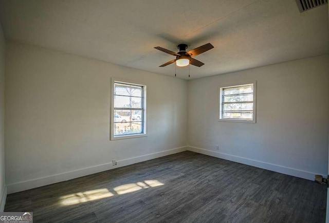 spare room featuring dark hardwood / wood-style floors, ceiling fan, and a healthy amount of sunlight