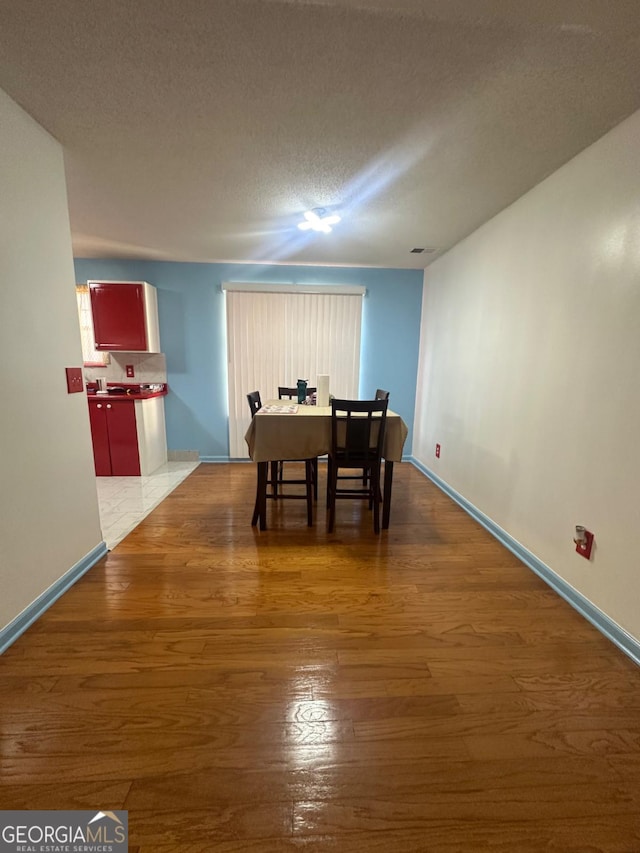 dining room featuring a textured ceiling and dark hardwood / wood-style floors