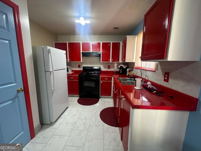 kitchen featuring a textured ceiling, white refrigerator, sink, and black range with gas cooktop