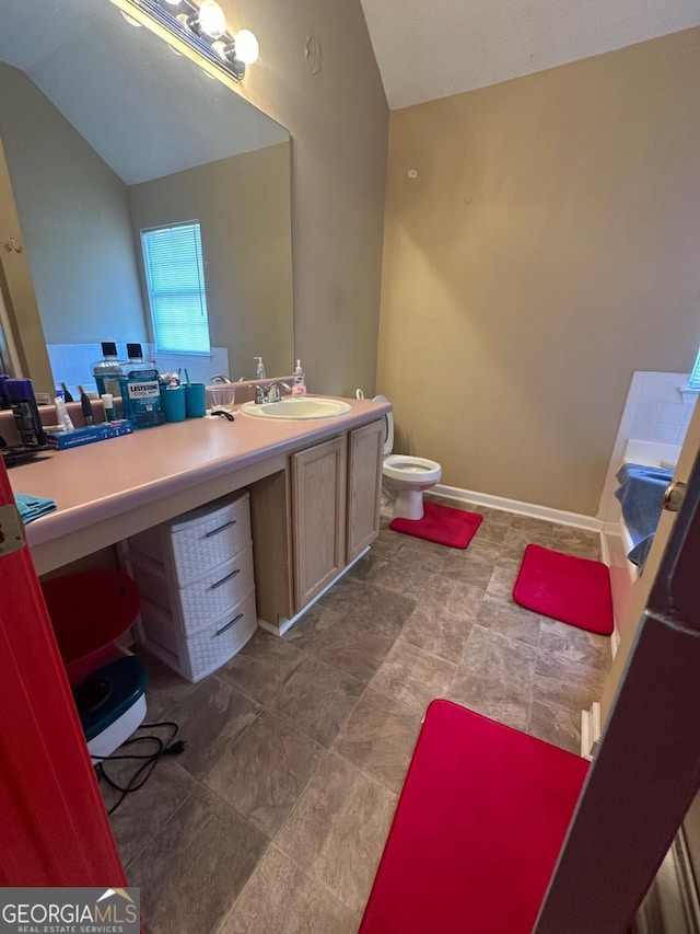 bathroom featuring vanity, toilet, and lofted ceiling