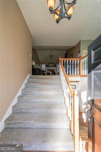 stairway featuring a textured ceiling and an inviting chandelier