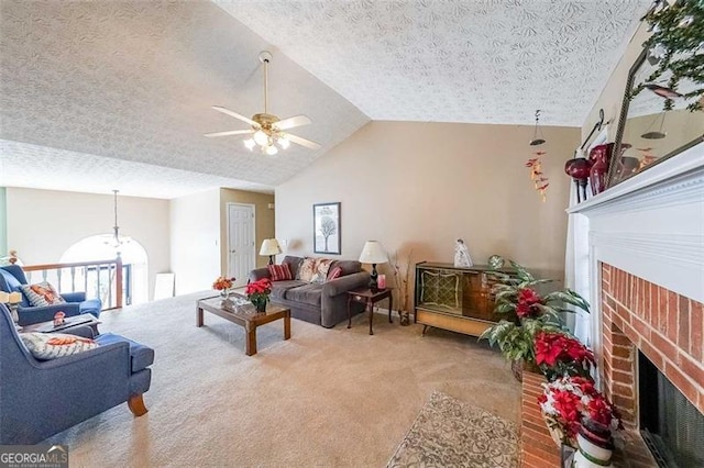 living room with carpet, a brick fireplace, vaulted ceiling, ceiling fan, and a textured ceiling