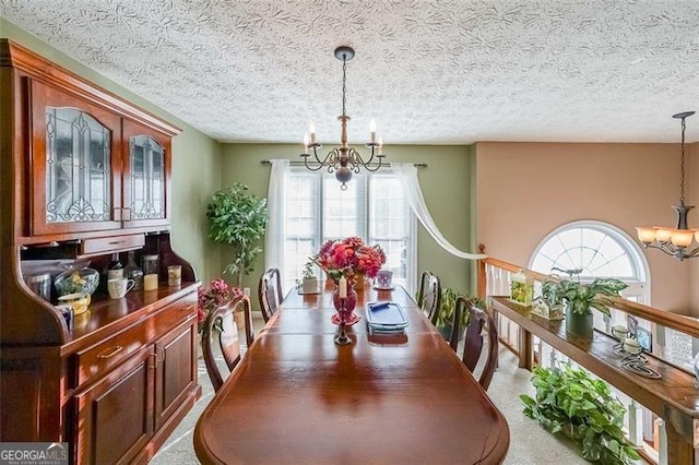 dining area with a textured ceiling, a healthy amount of sunlight, light carpet, and a chandelier