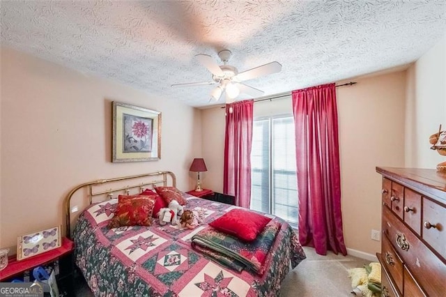 bedroom with ceiling fan, carpet floors, and a textured ceiling