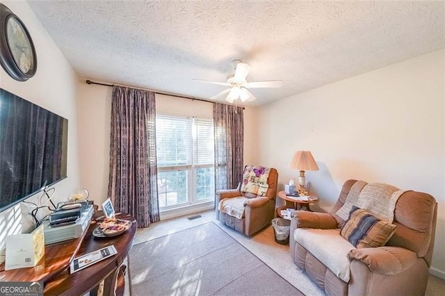 living area with carpet, ceiling fan, and a textured ceiling