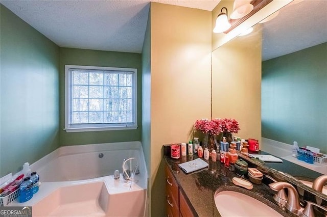 bathroom with a tub, vanity, and a textured ceiling