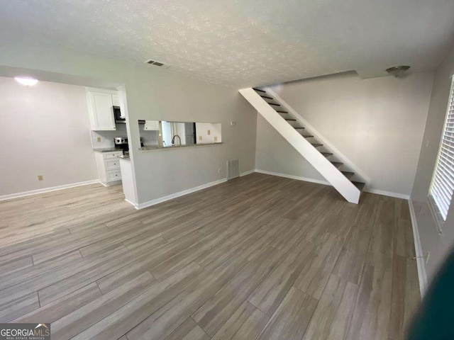 unfurnished living room with a textured ceiling and light wood-type flooring