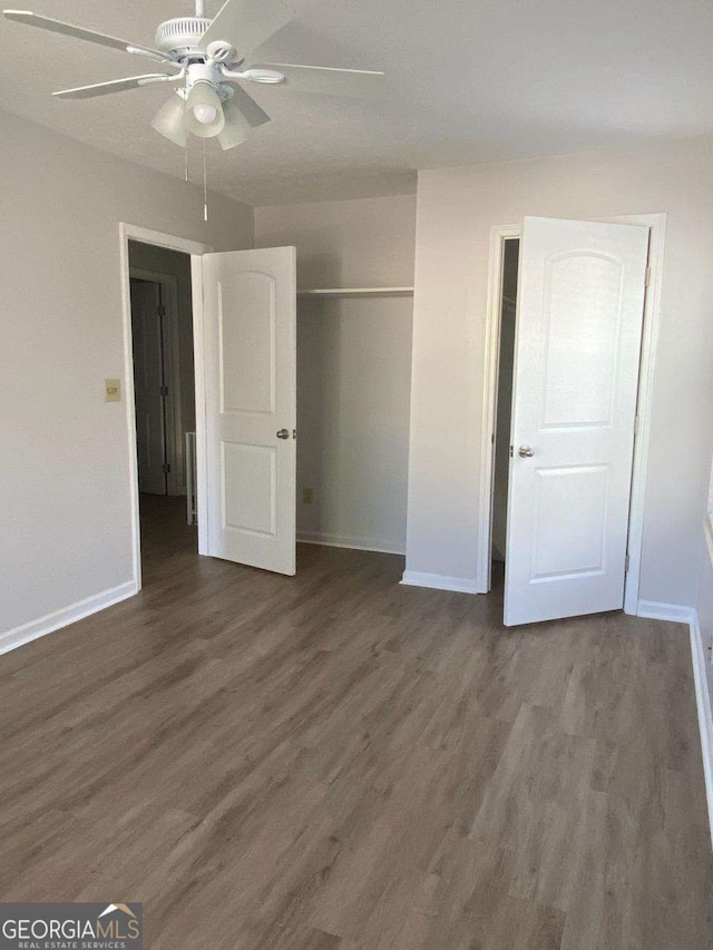 unfurnished bedroom with a closet, dark hardwood / wood-style floors, and ceiling fan