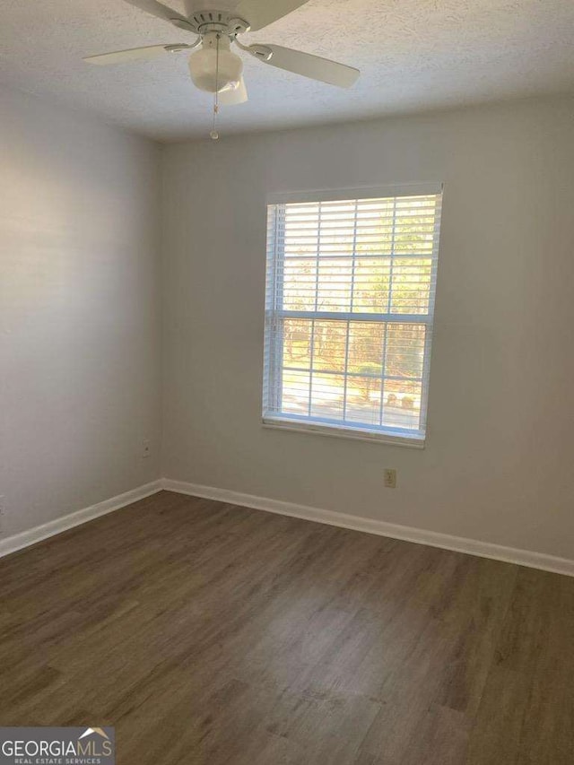 unfurnished room with a textured ceiling, ceiling fan, and dark wood-type flooring