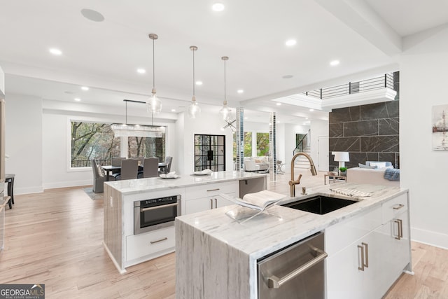 kitchen featuring a large island, sink, light stone counters, pendant lighting, and white cabinets