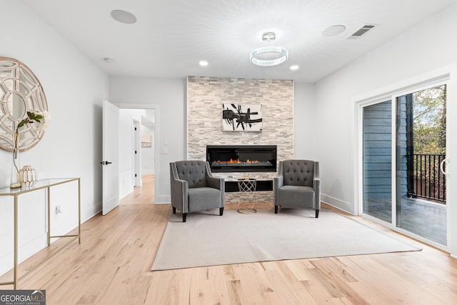 living area featuring a stone fireplace and light hardwood / wood-style flooring