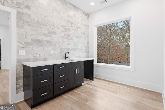 bar featuring sink, tile walls, and light wood-type flooring