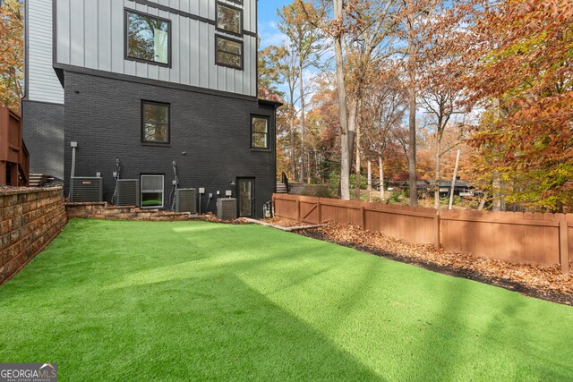 rear view of property with a lawn and central AC