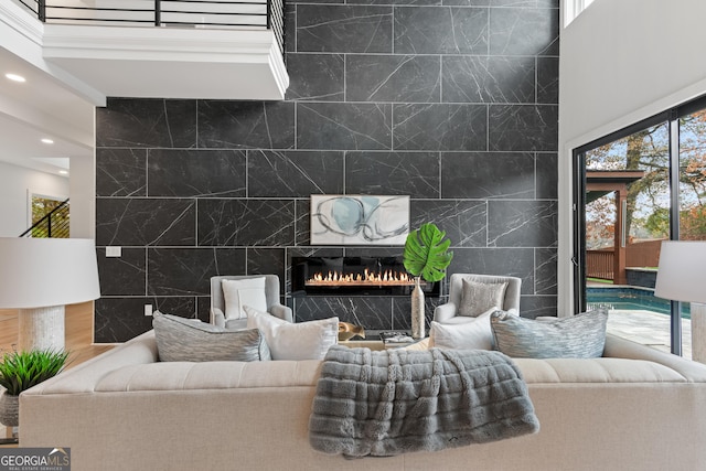 living room featuring a premium fireplace, a high ceiling, and tile walls