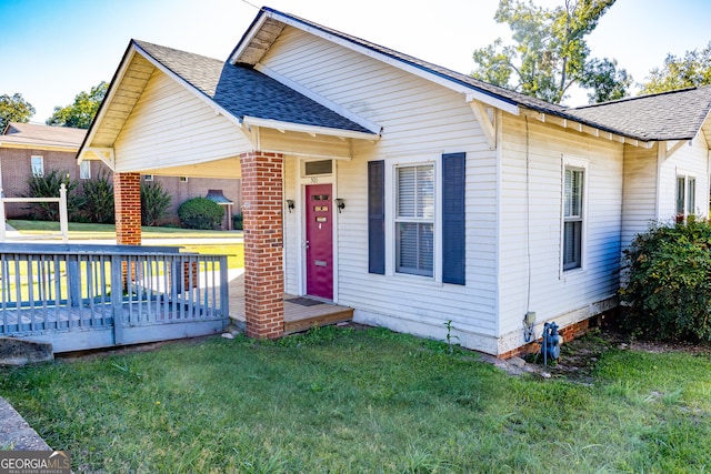 view of front facade with a wooden deck and a front lawn