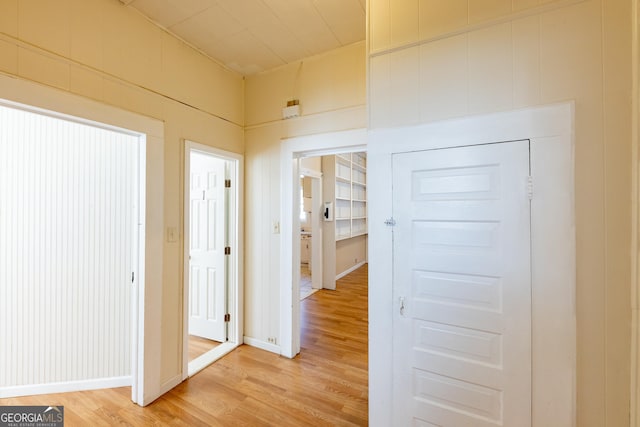 hall with hardwood / wood-style flooring and wooden walls